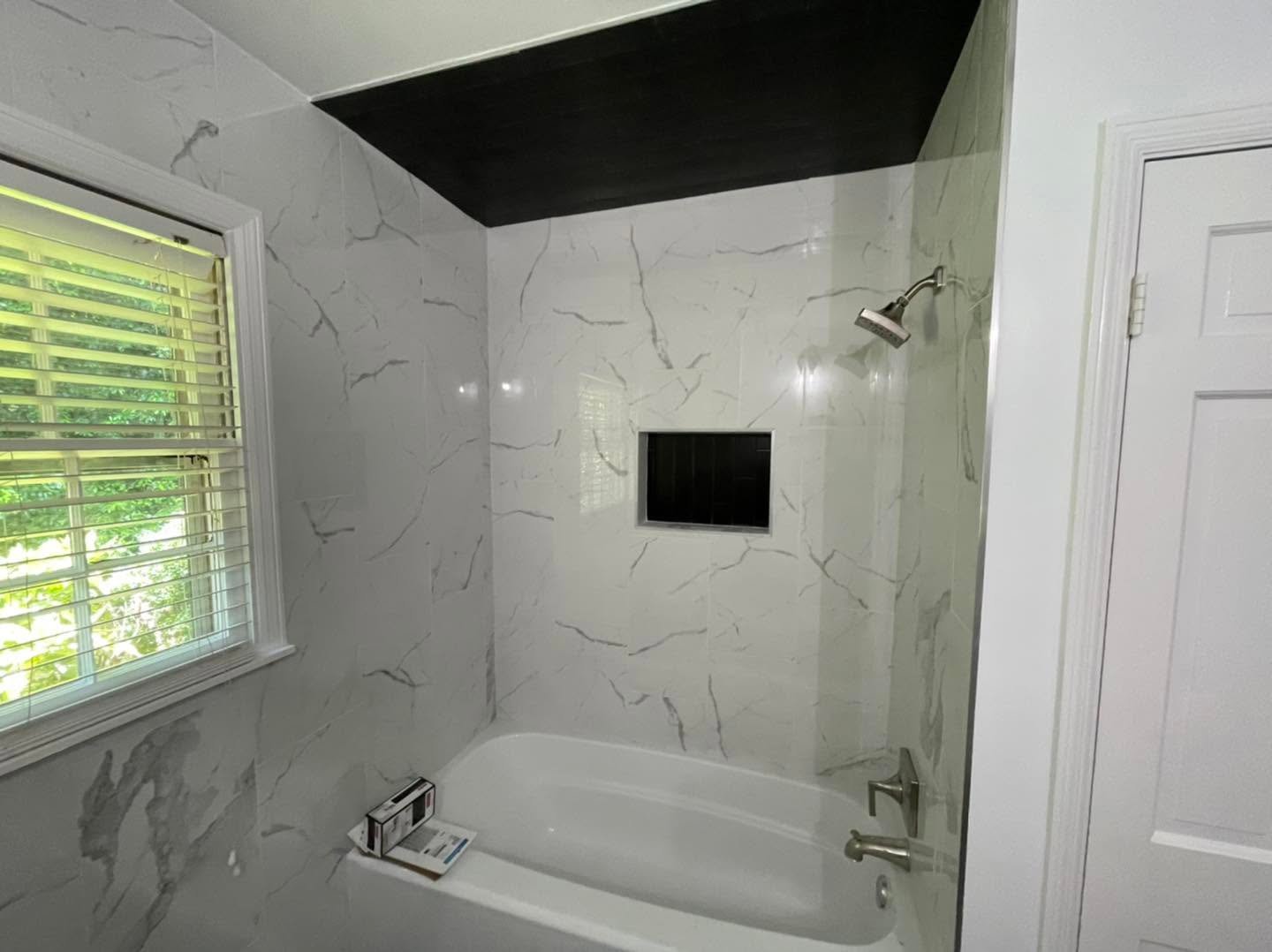 Tub surround with marble-look tile and black ceiling accent